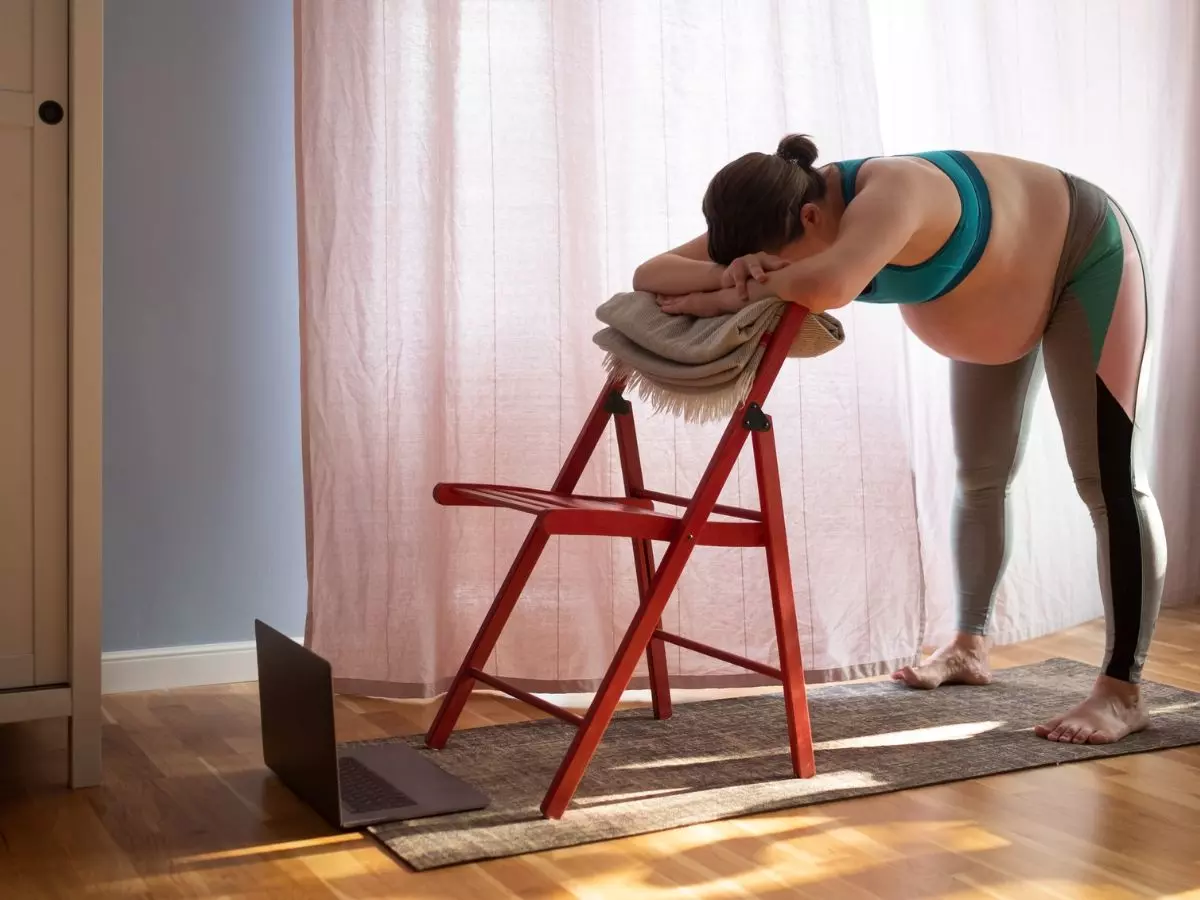 pregnant woman using chair as support for exercise