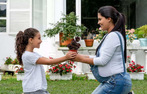 Mother and daughter planting a tree together outdoors