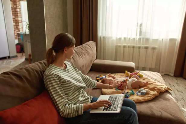 Beautiful mother works with laptop and sits with small child at home