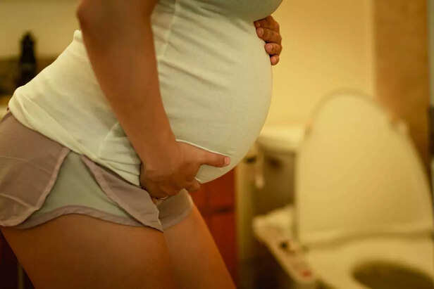 A pregnant woman rushing to toilet to pee.