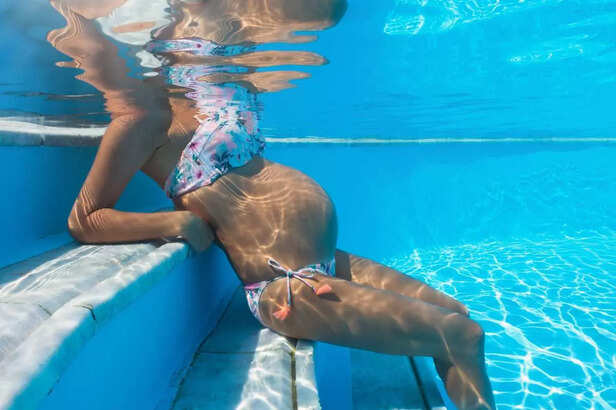 Underwater view of a pregnant woman sitting in the swimming pool