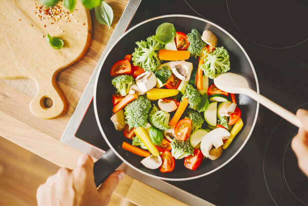 Man cooking fresh vegetables in pan